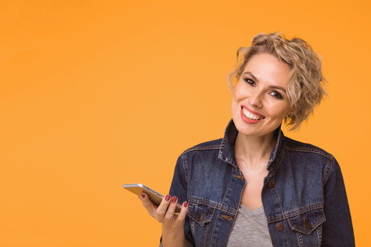 Fashion Pretty Woman Using Smartphone In Rock Black Style Over Colorful Orange Background