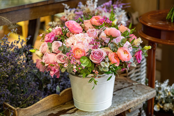 Beautiful multi-colored bouquet of mixed roses and other flowers in a shop. Fresh cut flowers placed in white flower pot.
