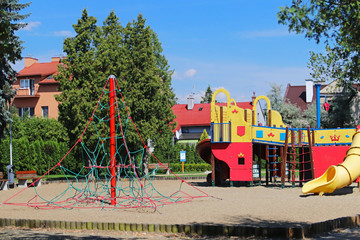 Yaslo, Poland - july 12 2018: Children's playground in the park amidst greenery. Multicolored swings and buildings for children from metal and wood. Place of play of the younger generation