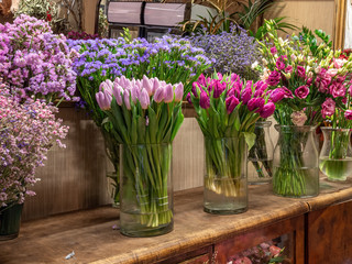 Beautiful colorful flowers for sale, placed in vases in flower shop. Tulips, roses and Estatiza.