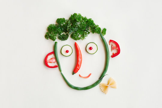 children creative and funny food, tasty and healthy kids breakfast, cute face made of vegetables, berries and greenery, parsley, zucchini, sweet pepper, asparagus, Italian pasta