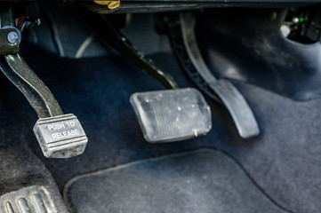 Focus on parking brake of vehicle with gas and brake pedals in the background 