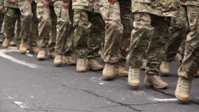 Army Soldiers parade through the streets in homecoming parade. They march in formation in camouflage. Marching. Slow motion