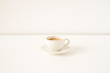 Cup of coffee with milk on white table. Minimal morning breakfast concept.
