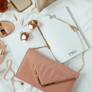 Pink styled women fashion composition with female accessories, bijouterie, accessories on white linen in bed. Flat lay, top view template for social media, website, magazine.