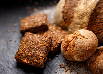 Wholemeal bread,  rolls and bread on a black background, close up view
