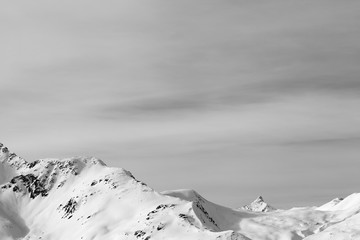 High mountains with snowy peak and sunlit cloudy sky at winter morning