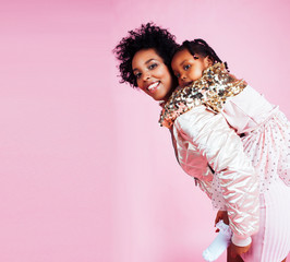 young pretty african-american mother with little cute daughter hugging, happy smiling on pink background, lifestyle modern people concept