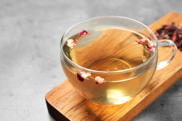Cup of green tea with dry flowers on grey table, closeup