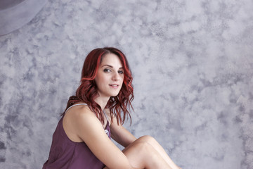 Young joyful girl with long legs sits on the floor