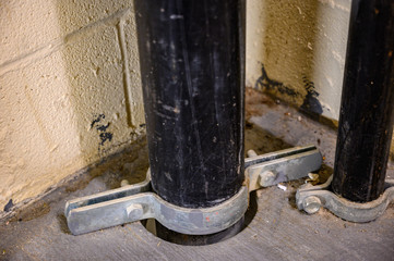 Clamp on metal pipe support bracket on concrete floor