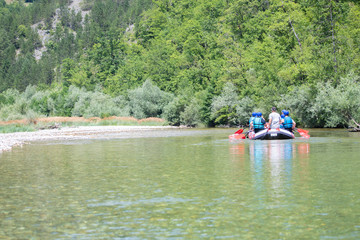 Fototapeta na wymiar Rafting team goes down the river on the beautiful sunny day. Back view.