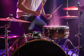 The drummer plays the drums. Beautiful blue and red background, with rays of light. Beautiful...