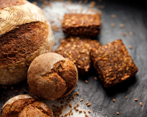 Wholemeal bread,  rolls and bread on a black background, close up view