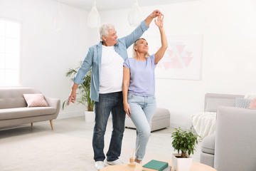 Happy mature couple dancing together in living room
