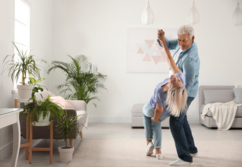 Happy mature couple dancing together in living room