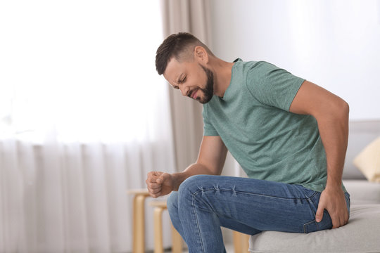 Man suffering from hemorrhoid in living room