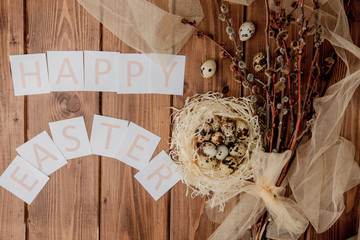 Flat lay composition of quail eggs and card with text Happy Easter on wooden table. Top view.