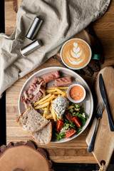 Substantial breakfast in a cafe with bacon, roasted sausage poached egg and salad