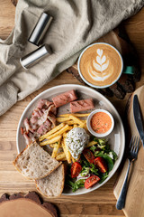 Substantial breakfast in a cafe with bacon, roasted sausage poached egg and salad