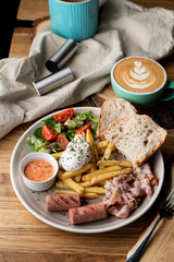 Substantial breakfast in a cafe with bacon, roasted sausage poached egg and salad