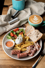 Substantial breakfast in a cafe with bacon, roasted sausage poached egg and salad