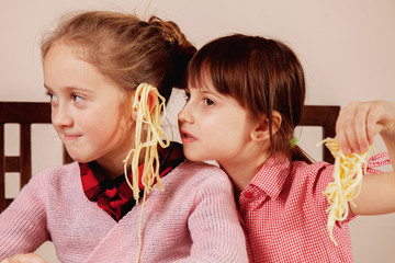 Noodles on the ears as symbol of deception and lies. Humorous portrait of two little cute child...