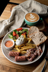 Substantial breakfast in a cafe with bacon, roasted sausage poached egg and salad