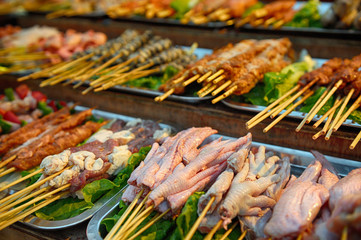 Chicken feet and other raw meat skewers ready to be grilled displayed at Chinese street market.
