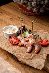 King prawns coated in bacon with sauce and green salad