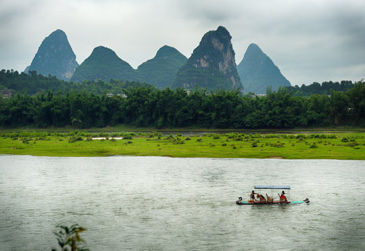 Tourist tour rafts boat on Li river, cruising between Gulin and Yangshou. This part of Guangxi province is very popular touristic destination because of unique mountains.