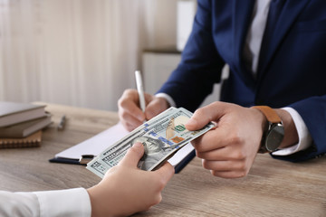 Woman giving bribe to man at table in office, closeup