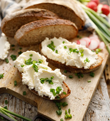 Sandwiches made of sourdough bread with the addition of curd cheese and fresh chopped scallion on a wooden board. The concept of a healthy, nutritious meal, breakfast.