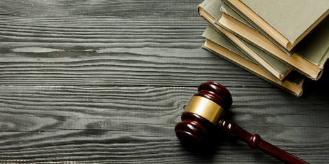 Law concept - Open law book with a wooden judges gavel on table in a courtroom or law enforcement...