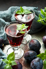 Plum wine or liquor on dark  background and ripe juicy plums