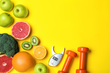 Fruits, vegetables, dumbbells and digital caliper on yellow background, flat lay with space for...