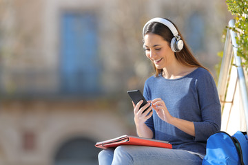 Happy student listening to music in a campus
