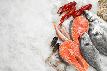 Fresh fish and seafood on ice, flat lay. Space for text