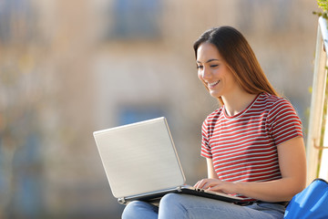Happy student e-learning using laptop in a campus