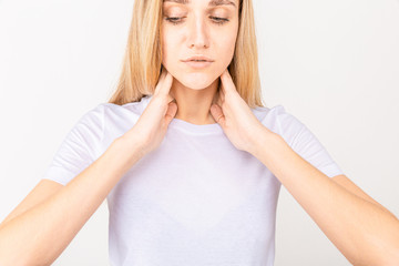 Female checking thyroid gland by herself. Close up of woman in white t- shirt touching neck with red spot. Thyroid disorder includes goiter, hyperthyroid, hypothyroid, tumor or cancer Health care.