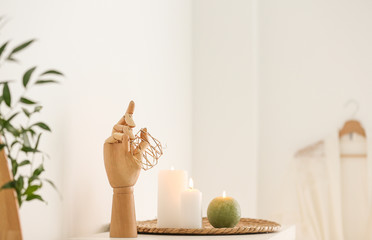 Wooden holder with jewelry and burning candles on white table in bathroom