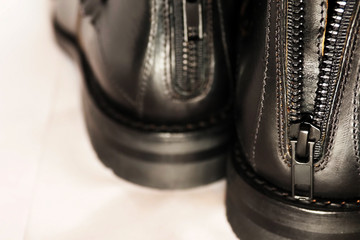 Fototapeta na wymiar Leather black boots with a zipper on the back, closeup.