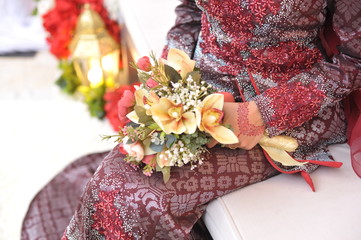 A Malaysian bride with a traditional wedding costume holding a bouquet of flower