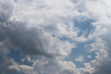 The sun shines through the cumulus clouds in the blue sky. Background and texture for artists and design. Bright light in the eyes. Water in gaseous state. The circulation of fluid in nature