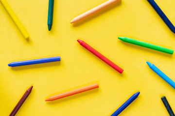 Yellow background with colorful wax pastel crayon pencils
