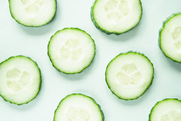Pattern with freshly cut cucumber slices on green background