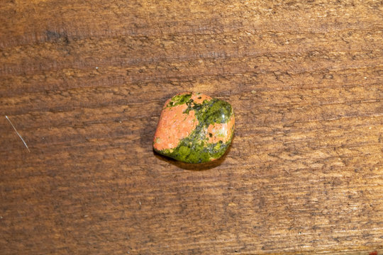 On a wooden background close-up semiprecious stone (gem) - Unakit.
