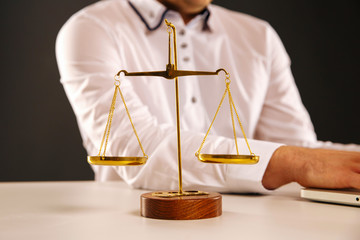 Weight scale of justice and man's hands on the background