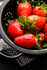 Fresh strawberries in a black colander, top view, close up