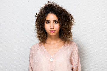 Close up serious young african american woman with curly hair by white background